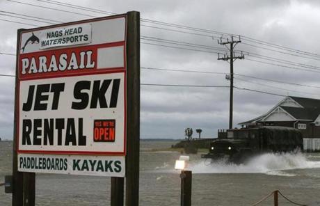 A Military truck drove  in front of a sign advertising jet ski rentals in Nags Head, N.C.
